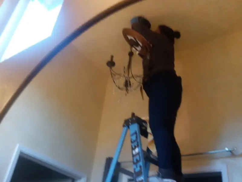 Electrician installing a chandelier in a Pendleton residence